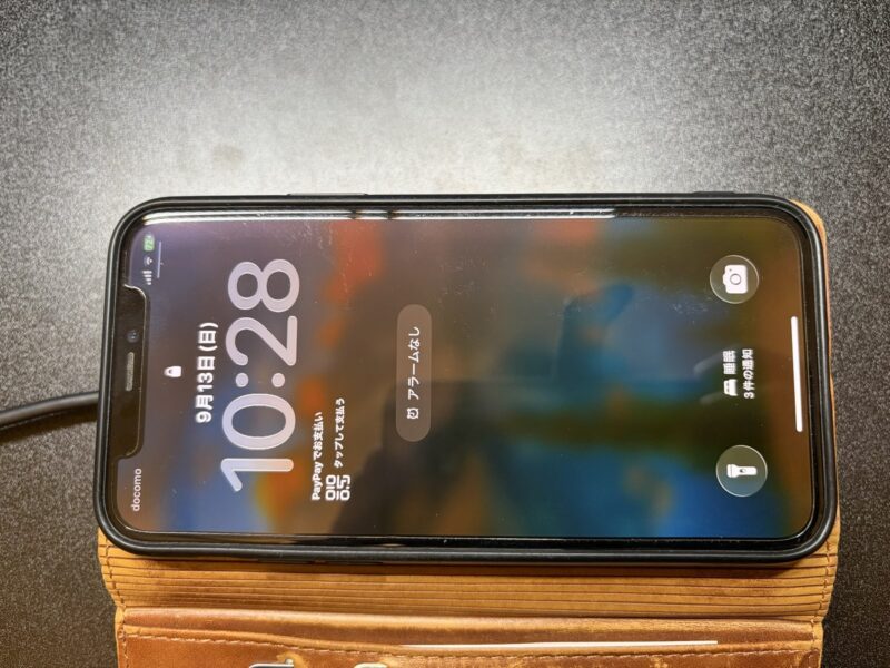手帳型ケースを付けたまま水平パッドに置いた状態。画面に充電中の表示が出ている